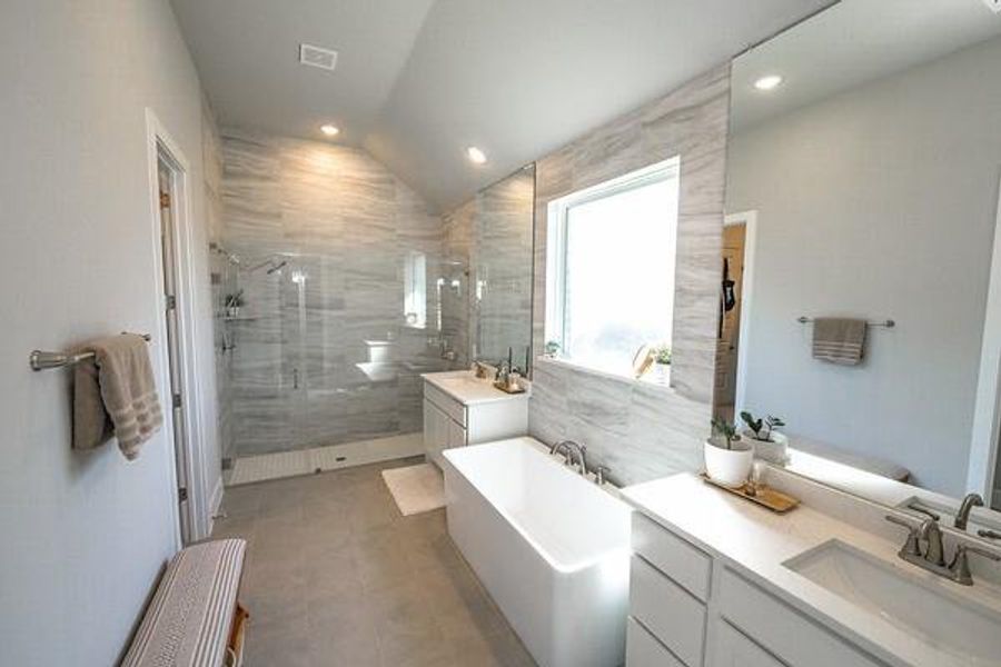 Bathroom featuring vanity, lofted ceiling, plus walk in shower, and tile walls