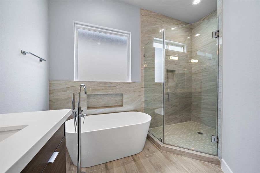 The elegant primary bathroom with dual sinks with a makeup vanity, a soaking tub, and a walk-in shower.
