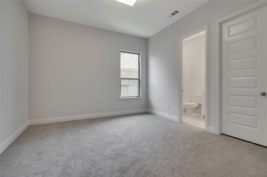 Unfurnished bedroom with ensuite bath and carpet floors