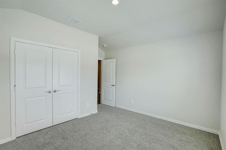 Bedroom with light colored carpet, and vaulted ceiling