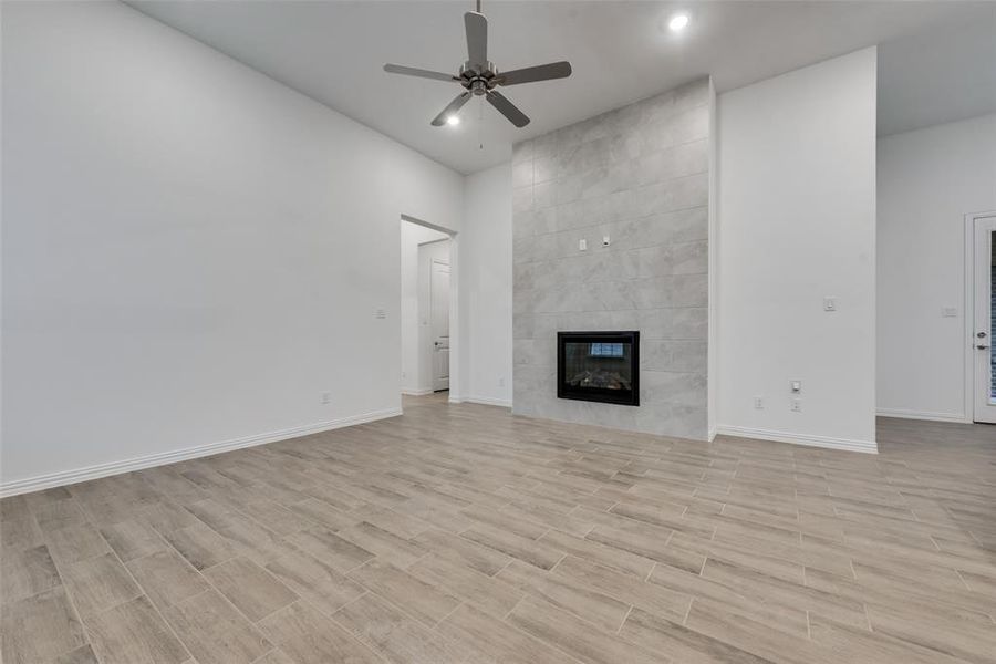 Unfurnished living room featuring tile walls, a tile fireplace, and ceiling fan