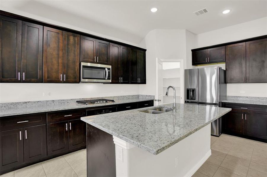 Kitchen featuring sink, a kitchen island with sink, light tile floors, and stainless steel appliances