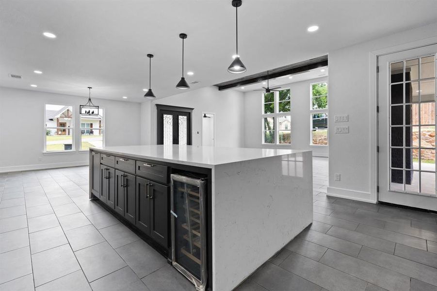 Kitchen featuring a center island, pendant lighting, beverage cooler, and tile patterned floors