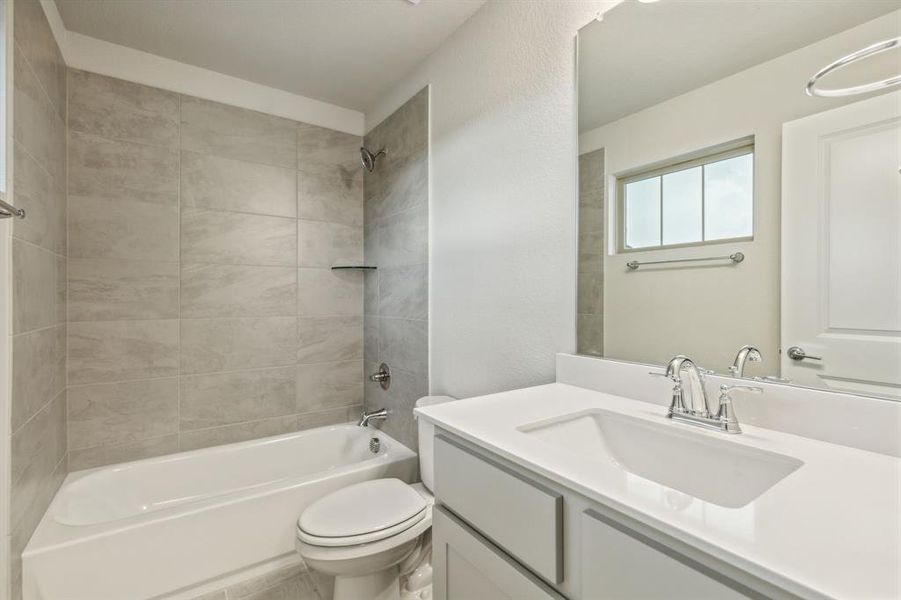 Full bathroom with tiled shower / bath, vanity, and toilet