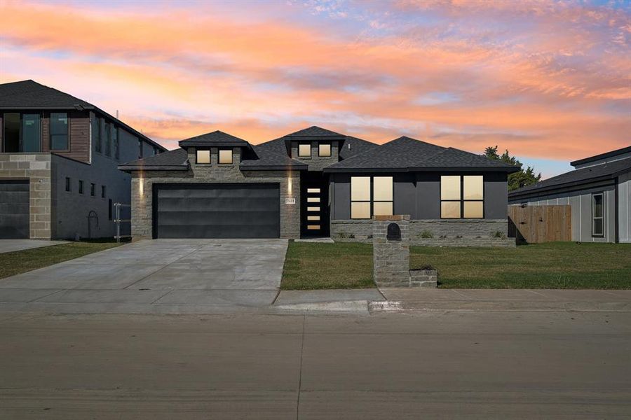 View of front of property featuring a garage and a yard