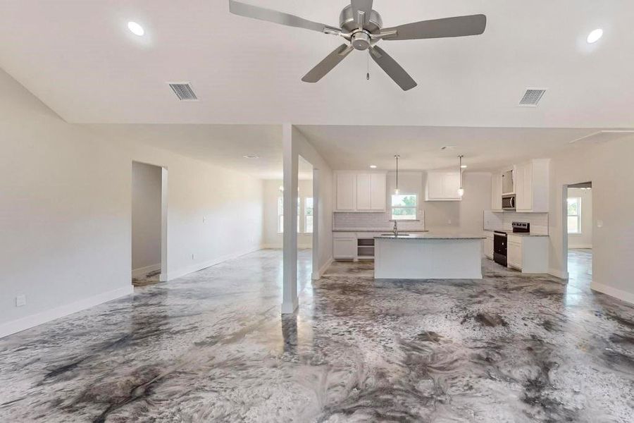 Unfurnished living room with sink, a healthy amount of sunlight, and ceiling fan