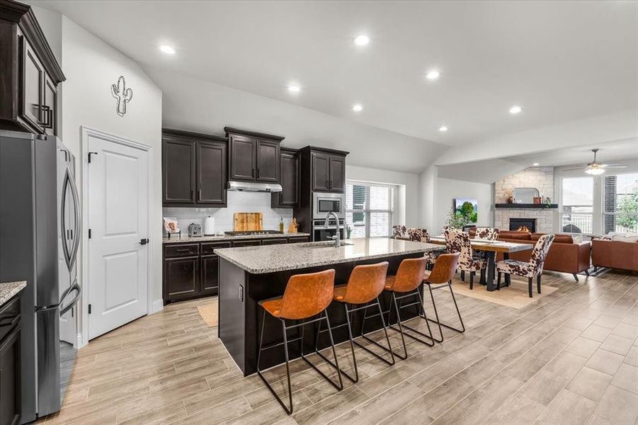 Kitchen with plenty of natural light, a kitchen island with sink, appliances with stainless steel finishes, and vaulted ceiling