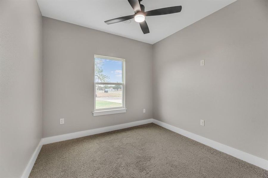 Carpeted spare room featuring ceiling fan