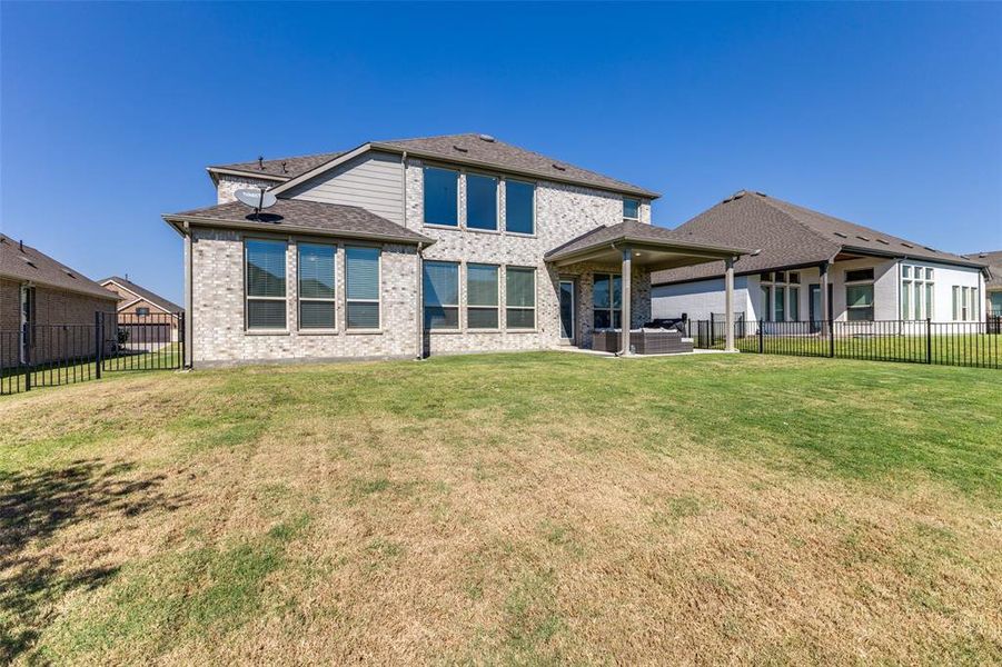 Rear view of property featuring large lawn and covered patio