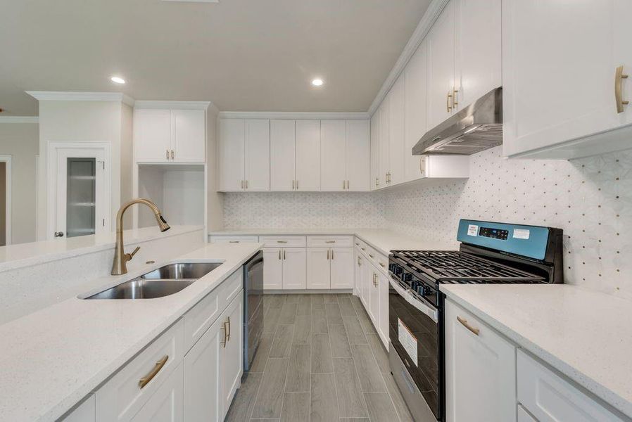 Kitchen featuring stainless steel appliances, backsplash, sink, white cabinets, and ornamental molding