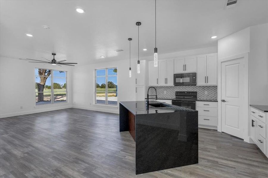 Kitchen with black appliances, dark hardwood / wood-style floors, sink, white cabinetry, and decorative light fixtures