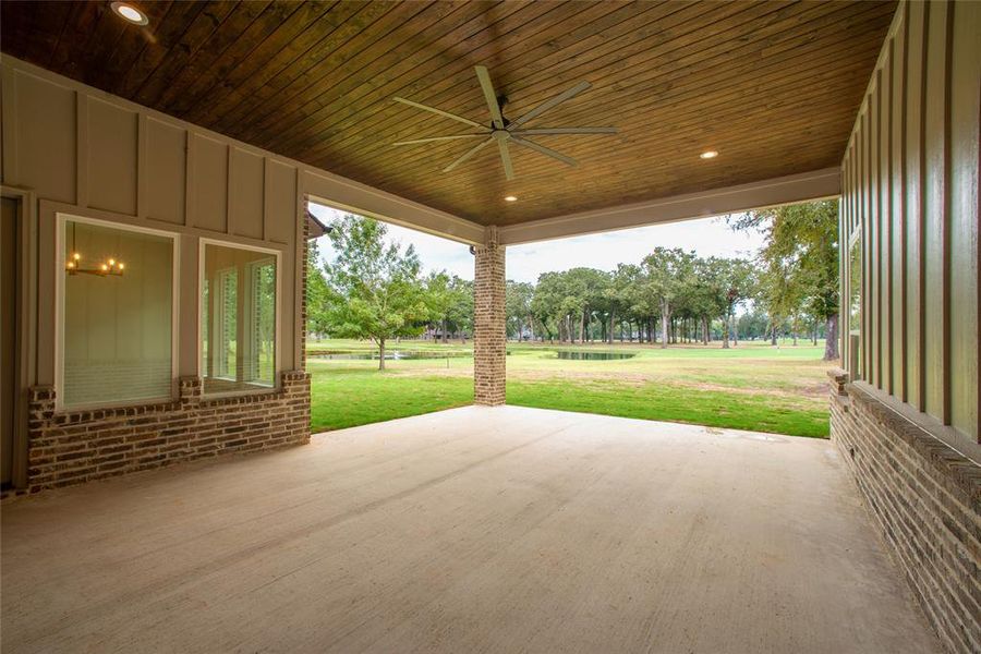 Large covered patio with stained ceiling and large fan with view of fountain.