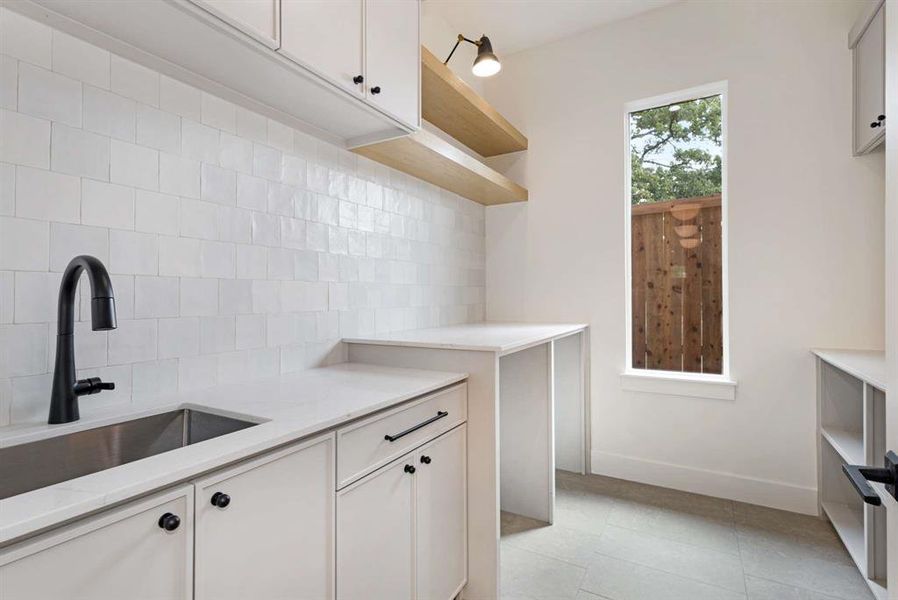 Kitchen with white cabinetry, sink, light tile patterned floors, and backsplash