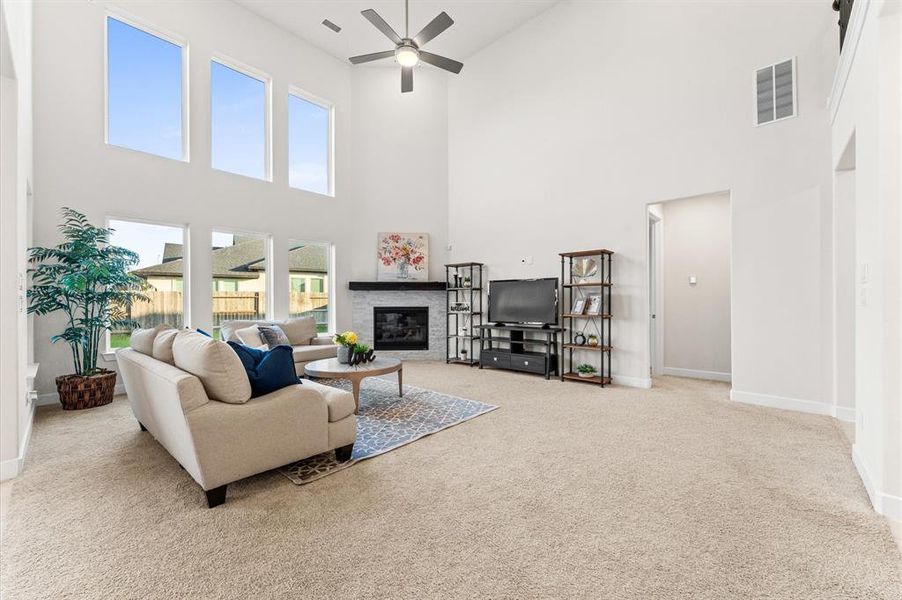 The spacious living area features high ceilings, a ceiling fan, and wide windows that offer a serene view of the backyard. A cozy fireplace adds warmth and charm, making it a perfect spot for relaxation or entertaining.
