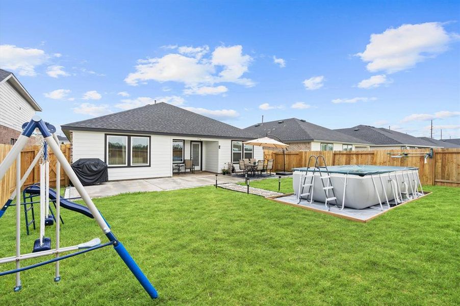 This photo showcases a spacious backyard with amenities including an above-ground pool (included), and a patio area for outdoor furniture, perfect for family entertainment and relaxation. The lawn is well-maintained and the fencing provides privacy.