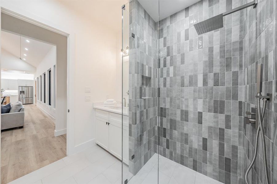 Bathroom featuring a shower with shower door, vanity, vaulted ceiling, and tile floors