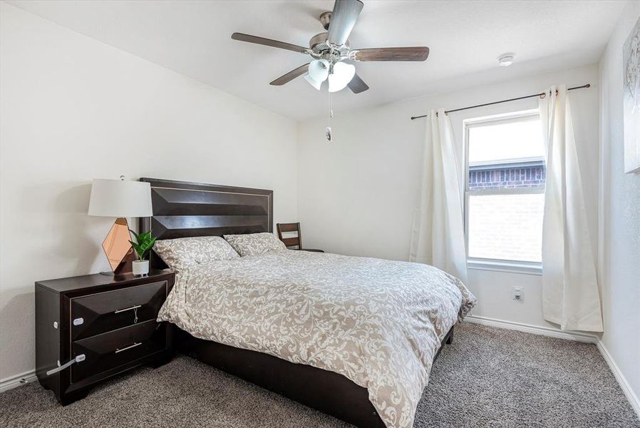 Carpeted bedroom featuring ceiling fan