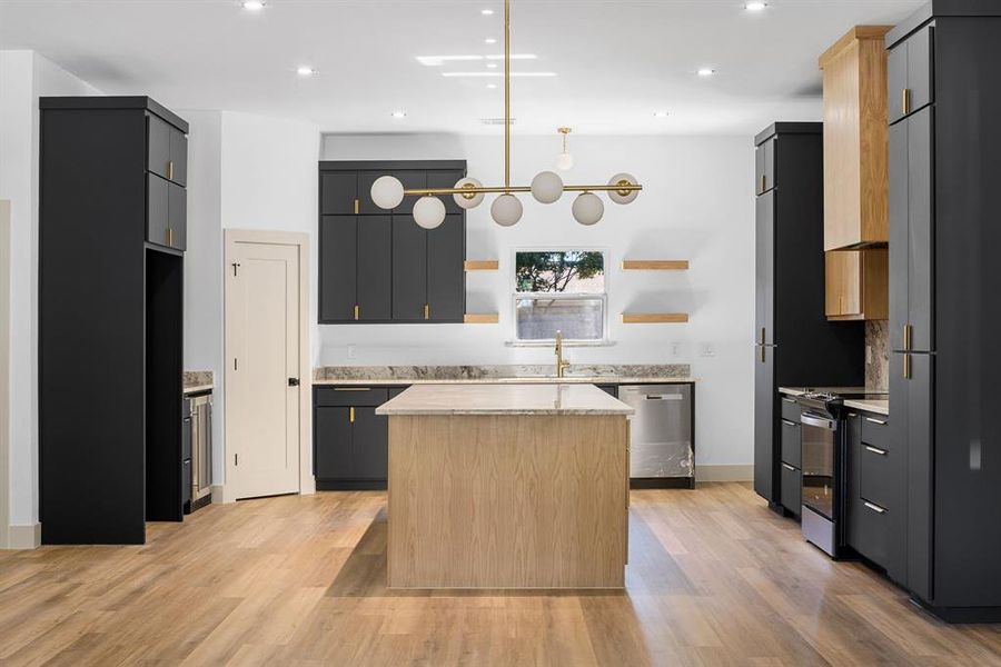 Kitchen with light brown cabinetry, a center island, light hardwood / wood-style flooring, and appliances with stainless steel finishes