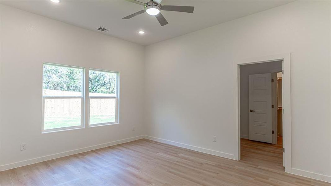 Primary bedroom with luxury vinyl plank flooring and ceiling fan.