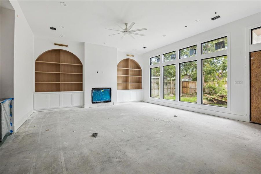 Peaceful views of the backyard space from this generous living room.  The fireplace will be complete with cast stone surround, and the white oak custom cabinetry are a gorgeous focal point of this well defined space.  Photo as of 9/3/2024