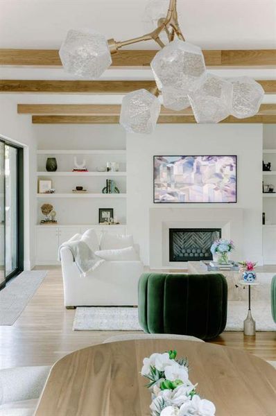 Living room featuring built in shelves, beamed ceiling, and hardwood / wood-style floors