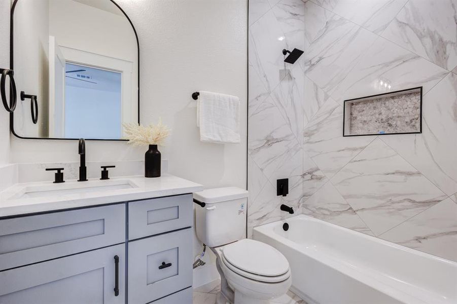 Full bathroom featuring tiled shower / bath combo, vanity, and toilet