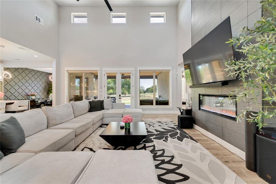 Living room featuring light hardwood / wood-style flooring, a fireplace, a high ceiling, and a wealth of natural light