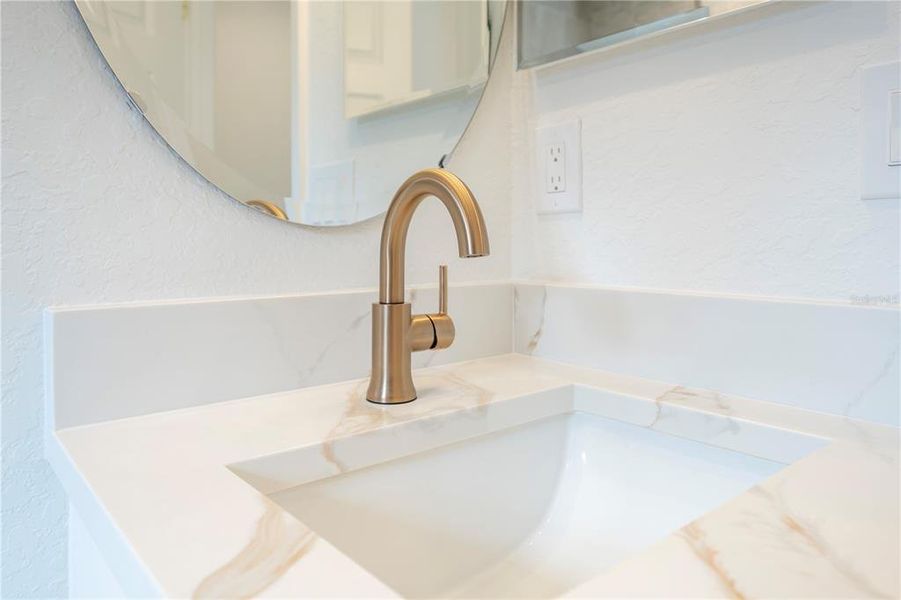 Gold fixtures in the guest bathroom and the same gold tones in the quartz countertops.