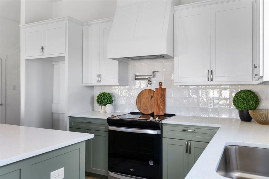 Kitchen featuring custom exhaust hood, stainless steel electric stove, tasteful backsplash, and green cabinets