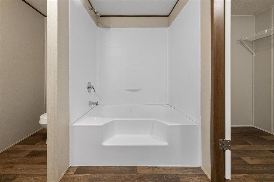 Bathroom featuring a textured ceiling, toilet, and wood-type flooring