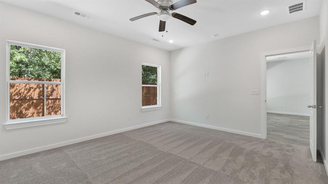 Spare room featuring a healthy amount of sunlight, light carpet, and ceiling fan