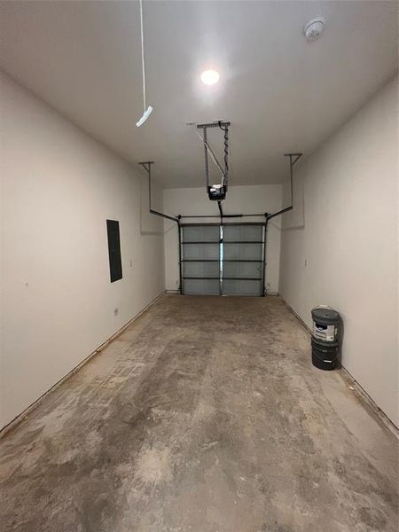 Garage featuring a garage door opener and electric panel