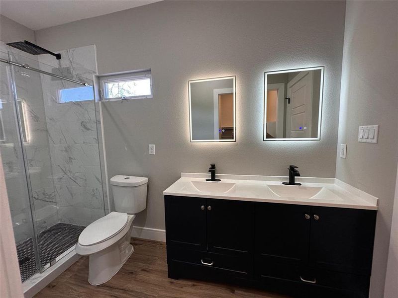 Primary bathroom with double vanity, a shower with glass door, individual mirrors with LED lights, anti-fog, and adjustable brightness.
