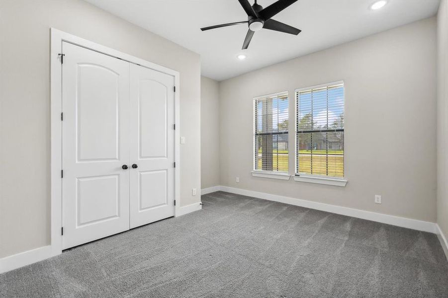 Unfurnished bedroom featuring carpet flooring, ceiling fan, and a closet