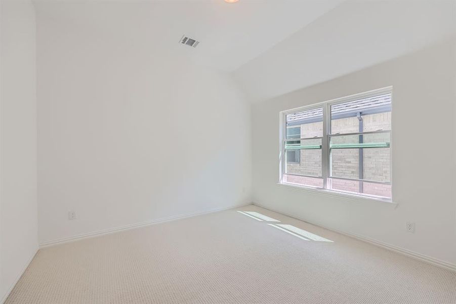 Spare room featuring light carpet and lofted ceiling