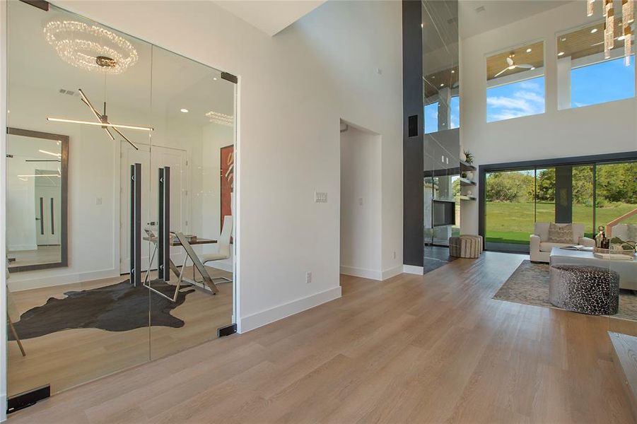 Living room featuring a healthy amount of sunlight, a towering ceiling, hardwood / wood-style floors, and a chandelier