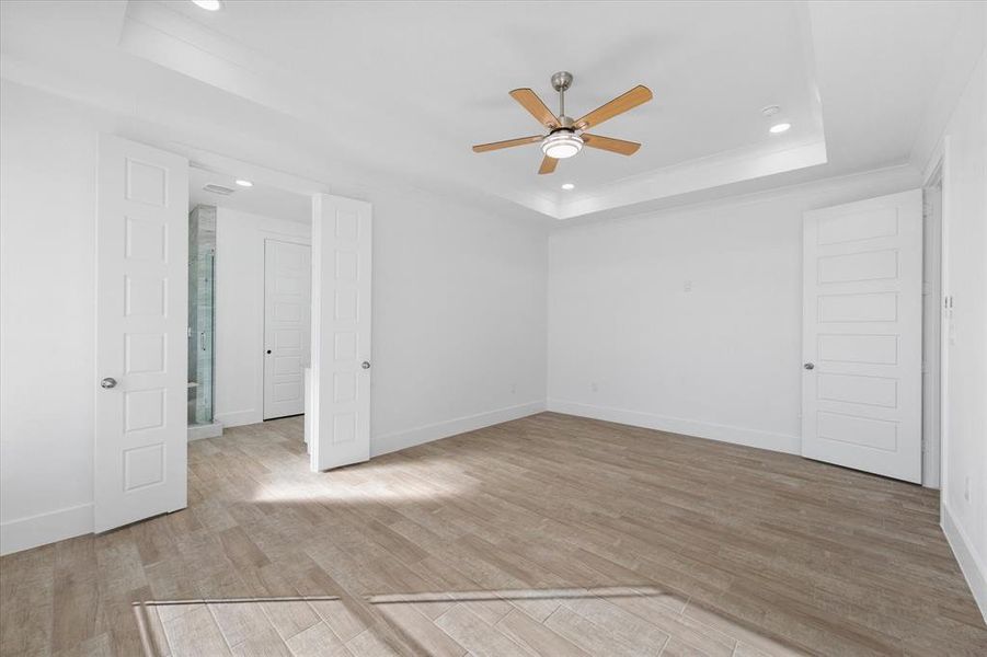 Spare room with ceiling fan, light hardwood / wood-style flooring, and a raised ceiling