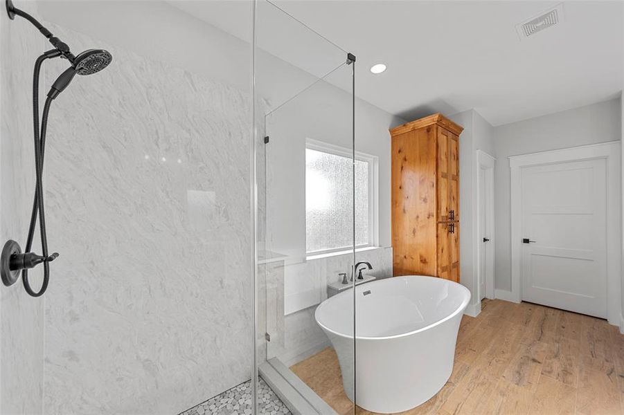 Bathroom with shower with separate bathtub and hardwood / wood-style flooring