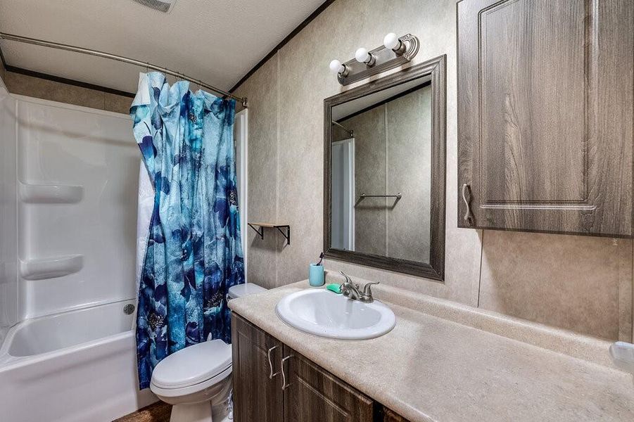 Full bathroom featuring shower / tub combo, a textured ceiling, vanity, and toilet