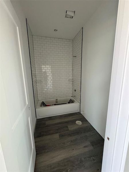 Bathroom with wood-type flooring and tiled shower / bath combo