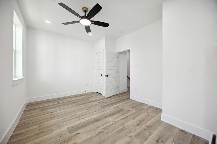 Secondary bedroom on third floor features high ceiling with modern ceiling fan and stylish upgraded flooring. It includes a built-in closet and ample natural light from a side window, promising a cozy and inviting space for personalization.