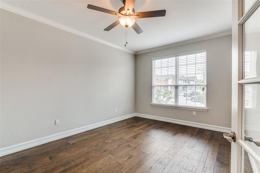 Unfurnished room featuring dark wood-type flooring, ceiling fan, a wealth of natural light, and crown molding