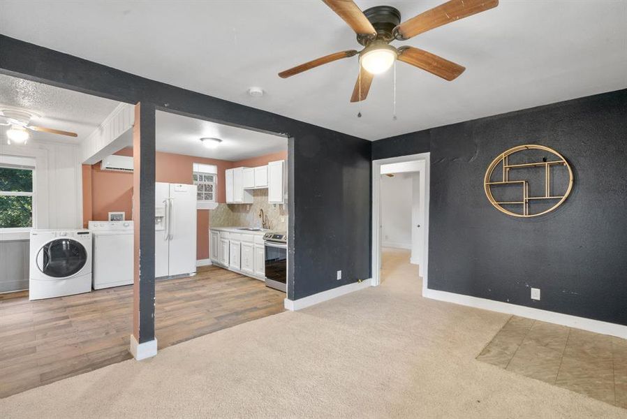 Unfurnished living room with ceiling fan, light colored carpet, separate washer and dryer, and sink