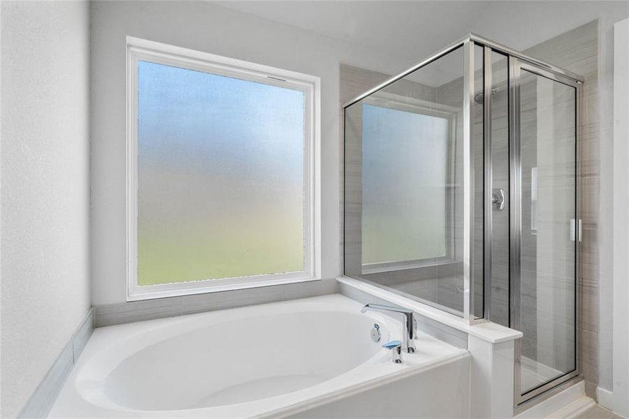 This primary bathroom is definitely move-in ready! Featuring dark framed walk-in shower with tile surround, and a separate garden tub for soaking after a long day with custom tile detailing.