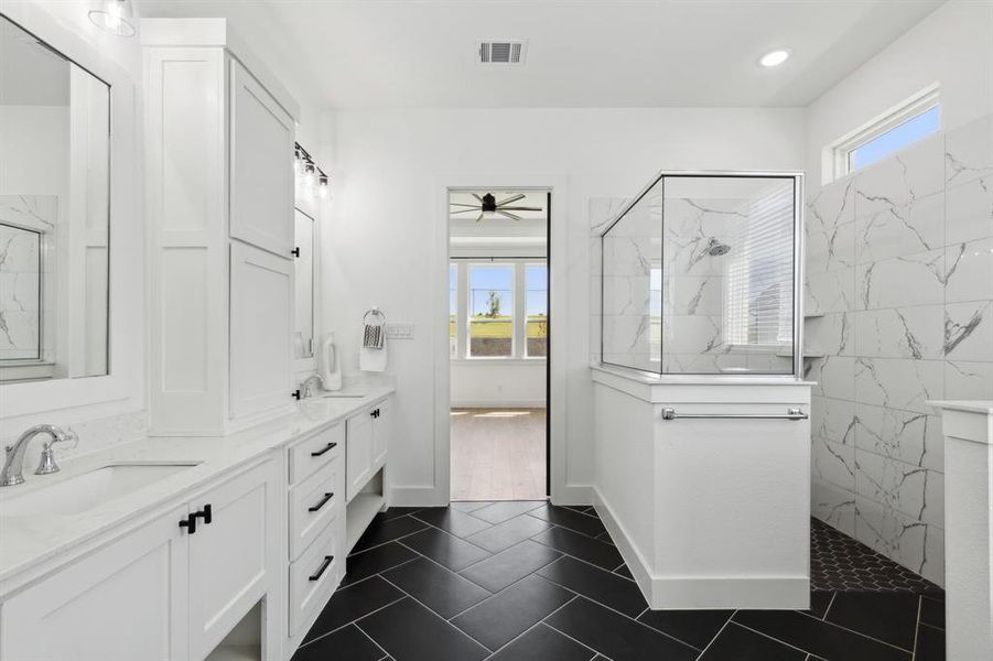 Bathroom featuring tiled shower, vanity, ceiling fan, and tile patterned flooring