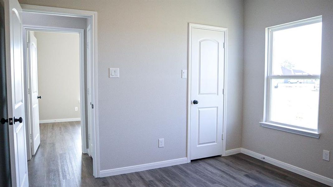 Unfurnished bedroom featuring multiple windows and dark hardwood / wood-style flooring