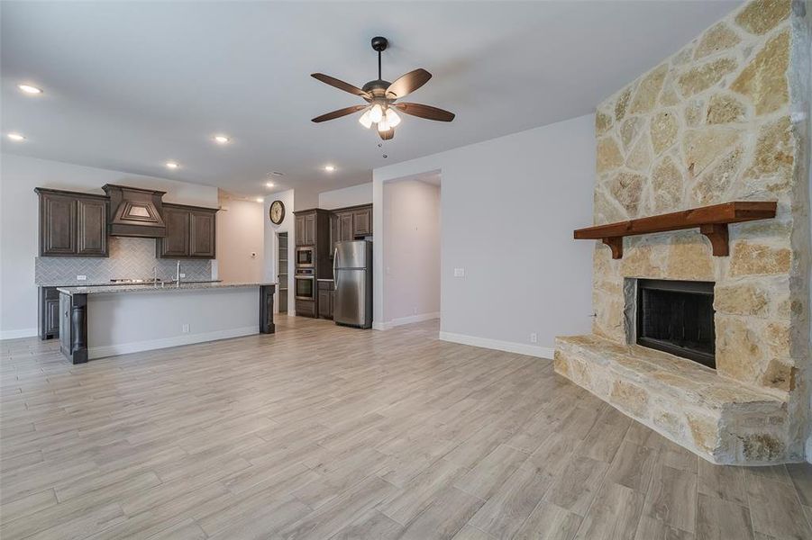 Unfurnished living room featuring light hardwood / wood-style flooring, a fireplace, and ceiling fan