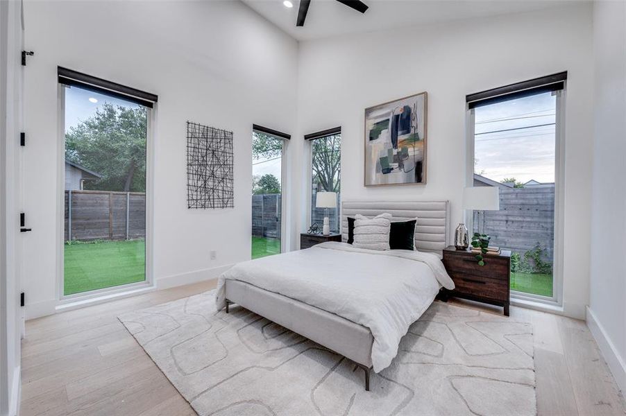 Bedroom with ceiling fan, high vaulted ceiling, and light wood-type flooring