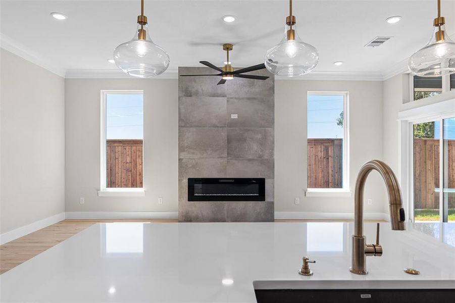 Kitchen with a tiled fireplace, crown molding, ceiling fan, light hardwood / wood-style flooring, and sink