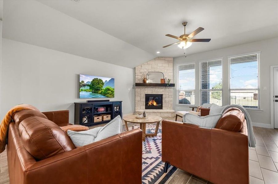 Living room with ceiling fan, light hardwood / wood-style floors, lofted ceiling, and a fireplace